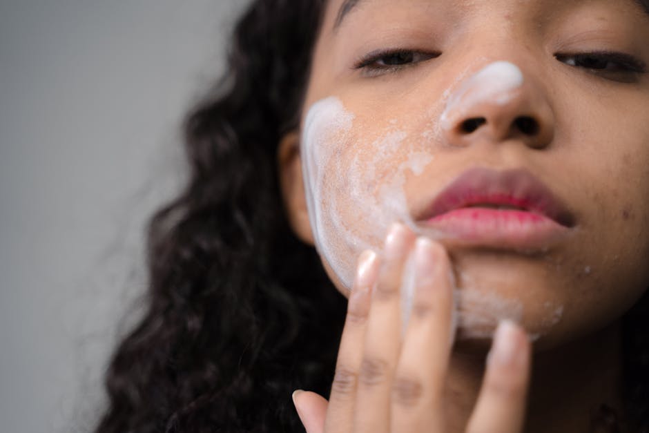 A woman applying skincare cream on her face, focusing on self-care and beauty routines